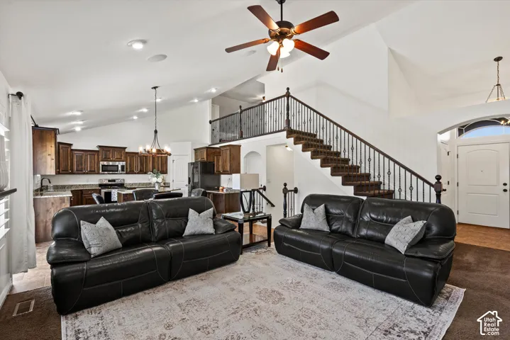 Vaulted ceilings, a dark wood-finish staircase with wrought iron balusters, a well-appointed kitchen with dark wood cabinetry, and a ceiling fan