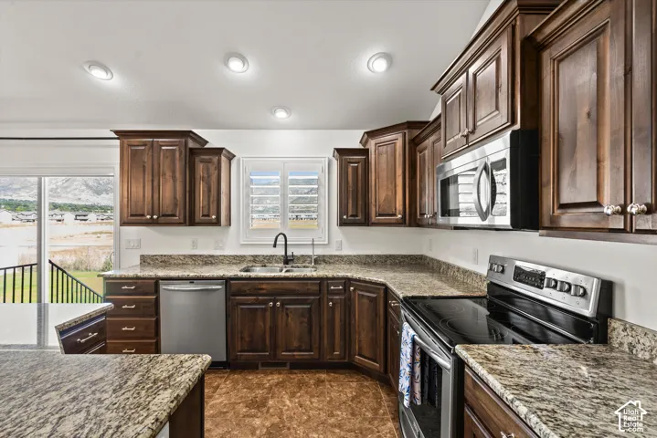 Kitchen featuring wood-finish cabinetry, speckled countertops, stainless steel appliances, and recessed lighting