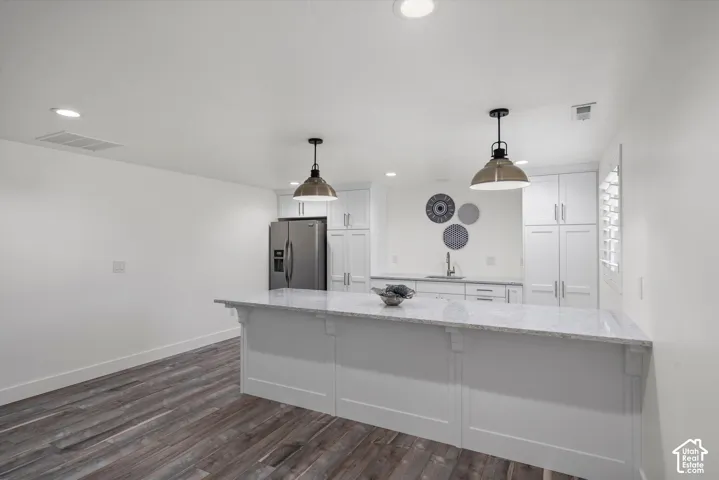 Kitchen featuring a central island with a light-toned countertop, white cabinetry, stainless steel appliances, and wood-finish flooring