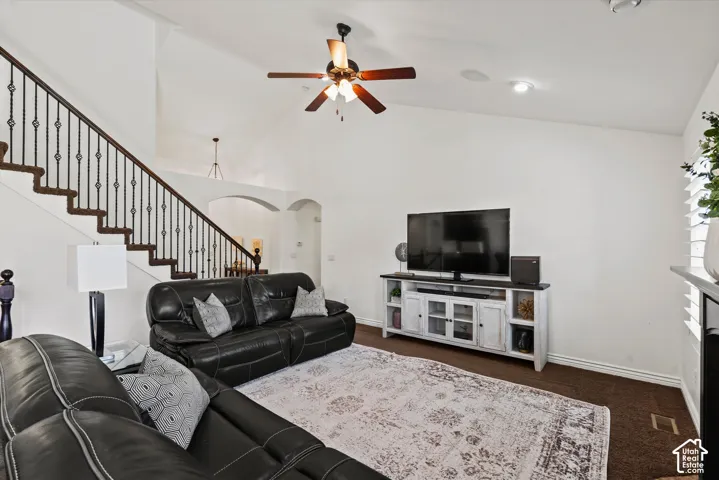 Vaulted ceiling with a ceiling fan, wrought iron stair railing, recessed lighting, and archways
