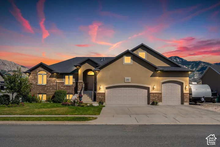 Two-car garage with arched doors, brick and stucco exterior, arched entry, and a prominent mountain backdrop