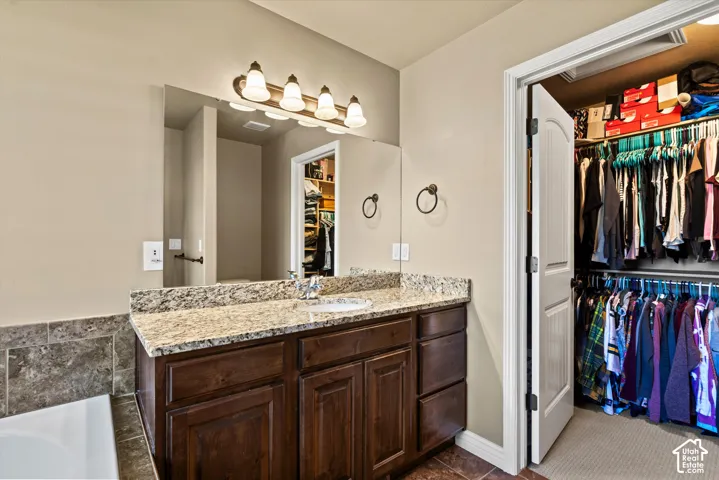 Single vanity with a granite countertop, undermount sink, and wood-finish cabinetry