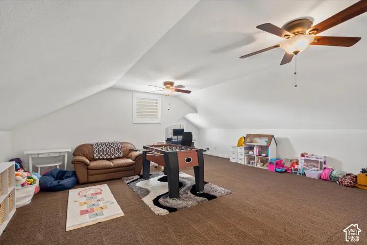 Sloped ceilings with recessed lighting, brown carpeted flooring, and two ceiling fans with integrated lighting