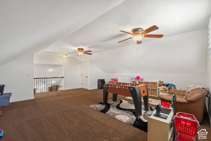 Expansive bonus room with sloped ceilings, two ceiling fans with integrated lighting, and a partial open railing