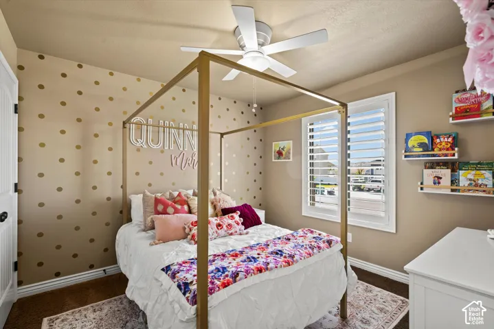 Room featuring a ceiling fan with integrated lighting, window with plantation shutters, baseboard molding, and wall-mounted shelving