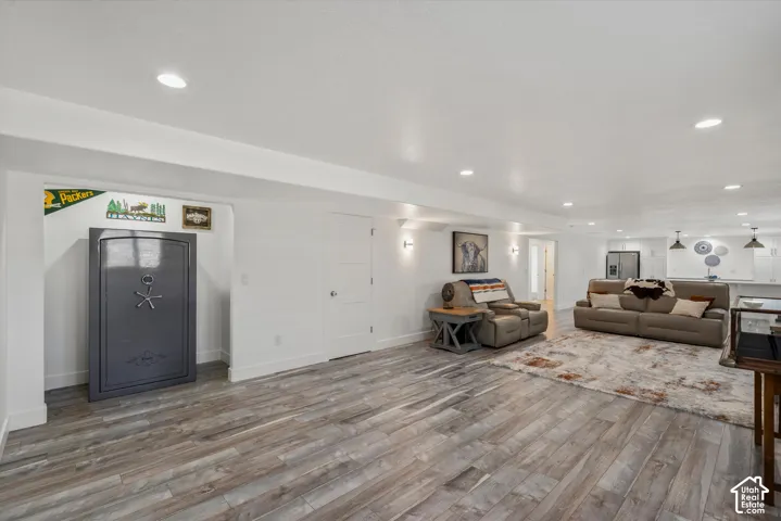 Recessed lighting illuminates the expansive space, featuring wood-finish flooring and white walls