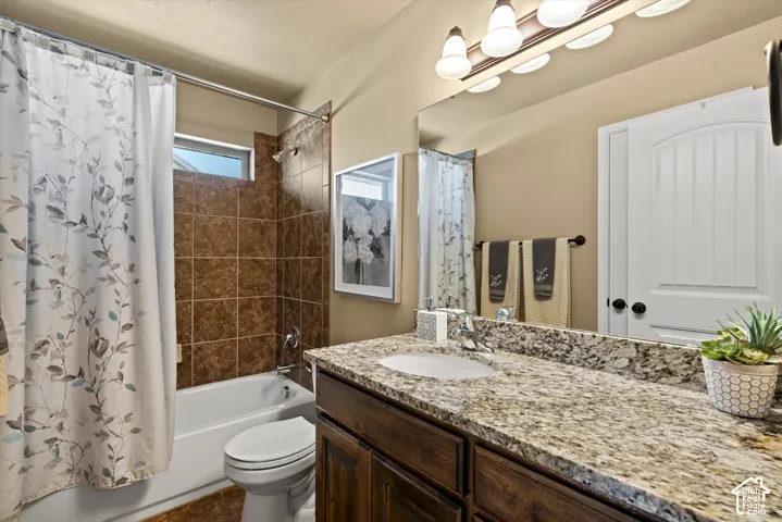 Bathroom featuring a built-in vanity with a granite-style countertop, undermount sink, and a large mirror