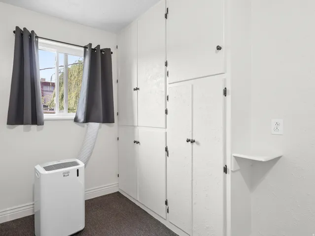 Built-in white cabinetry with dark hardware, a single window, and a wall-mounted shelf
