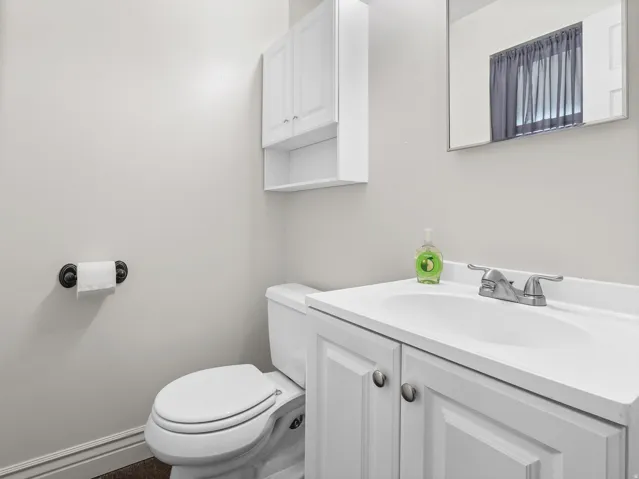 White vanity with integrated sink, chrome faucet, wall-mounted mirror, and white wall cabinet with open shelving
