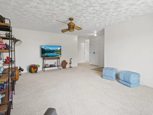 Wall-to-wall carpeting, white walls, and a ceiling fan with light