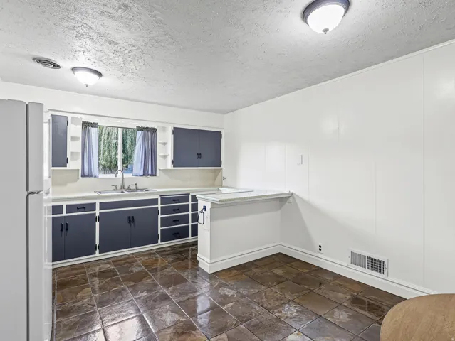 Kitchen featuring dark-toned cabinetry, light countertops, and a stainless steel sink with a gooseneck faucet