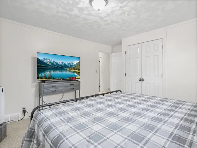 White walls with white trim, textured ceiling, flush mount ceiling light, and built-in closet with panel doors