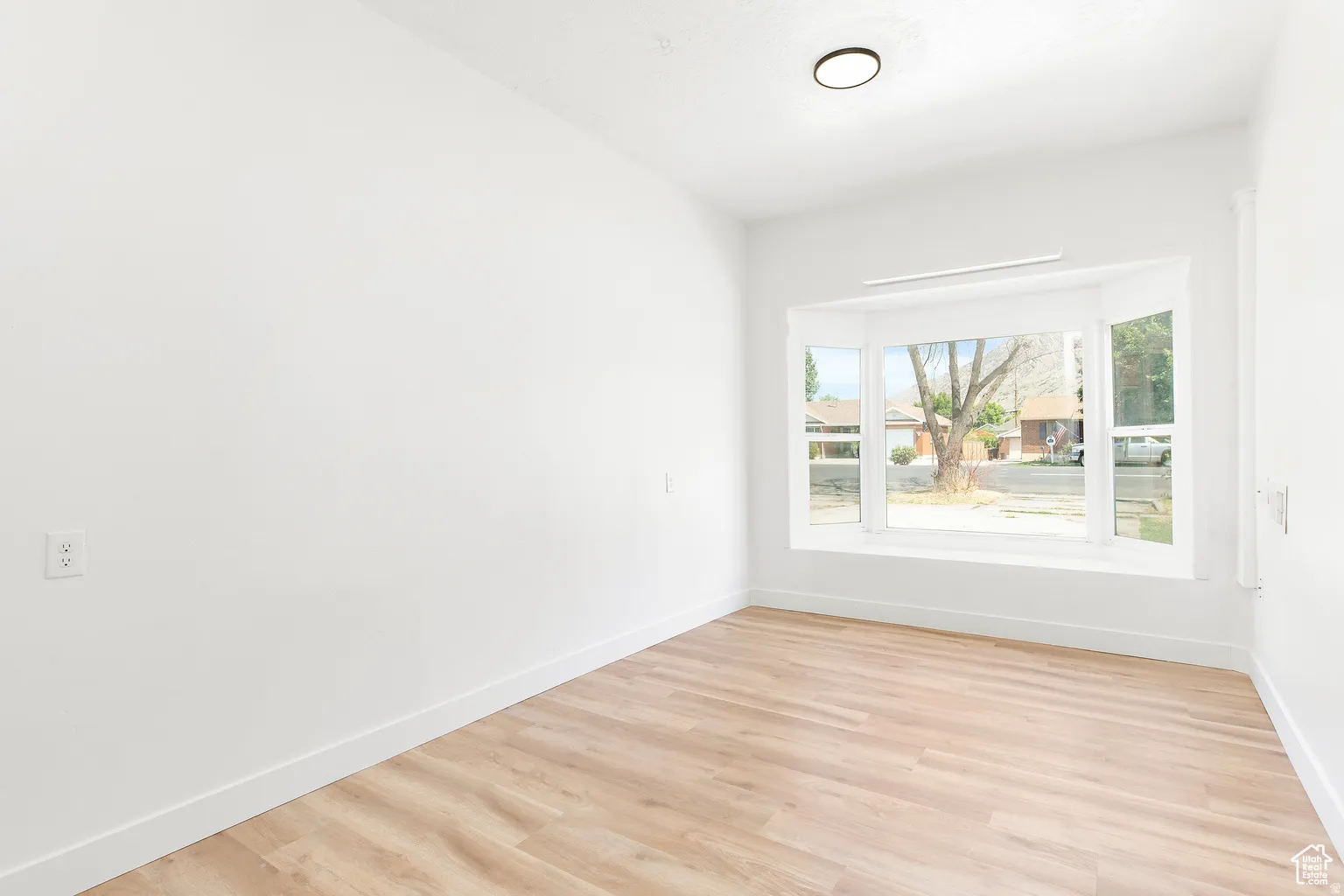 Recessed lighting, bay window, light wood-finish flooring, and white painted walls