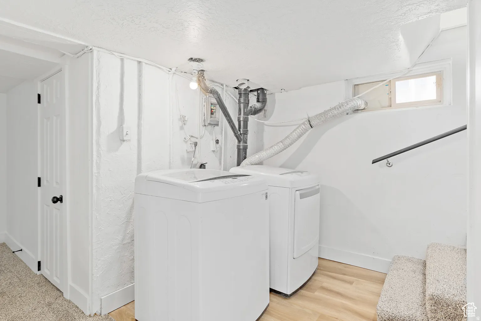 Laundry area featuring a washer and dryer, wood-finish flooring, and a window