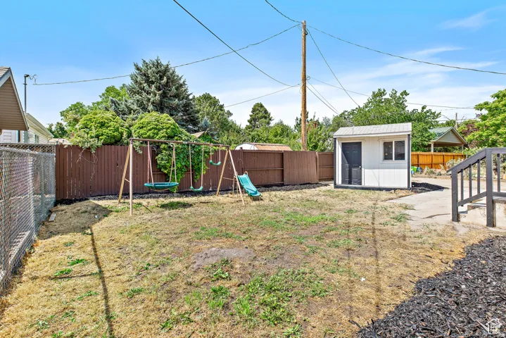Fenced backyard featuring a storage shed, wooden privacy fencing, chain link fencing, and exterior stairs