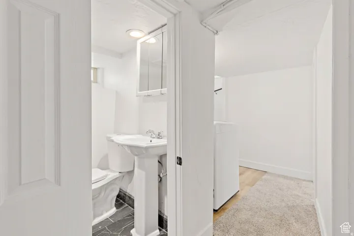 Bathroom featuring a pedestal sink, toilet, and mirrored medicine cabinet