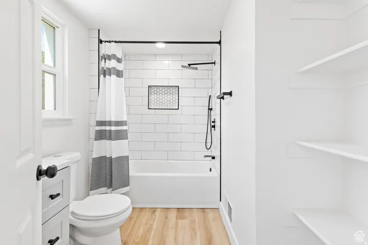 Bathroom featuring a white bathtub with subway tile surround, matte black shower fixtures, and a decorative hexagonal tile niche