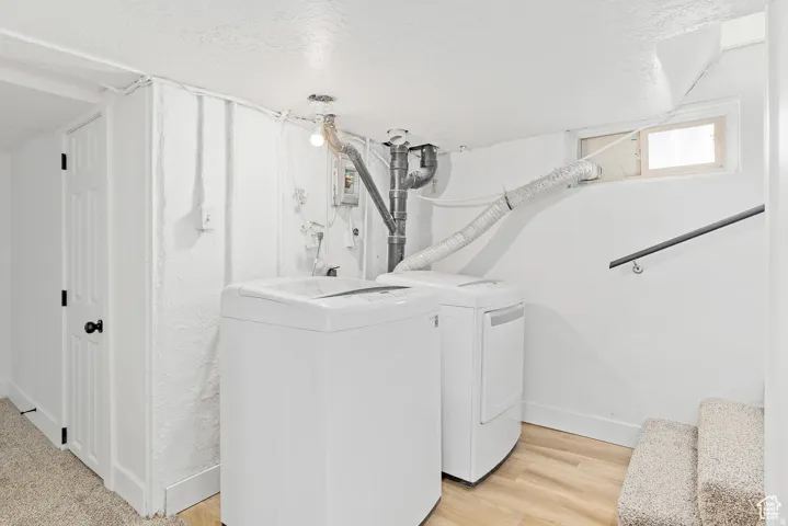 Laundry area featuring a washer and dryer, wood-finish flooring, and a window
