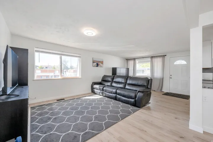 Recessed lighting, light wood-finish LVP flooring, and multiple windows with blinds
