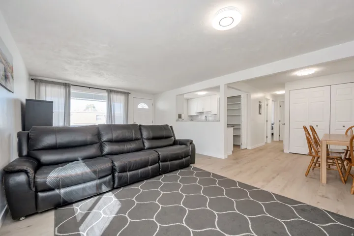 Recessed lighting, wood-finish flooring, white paneled doors, and a partial view of the kitchen with new white cabinetry
