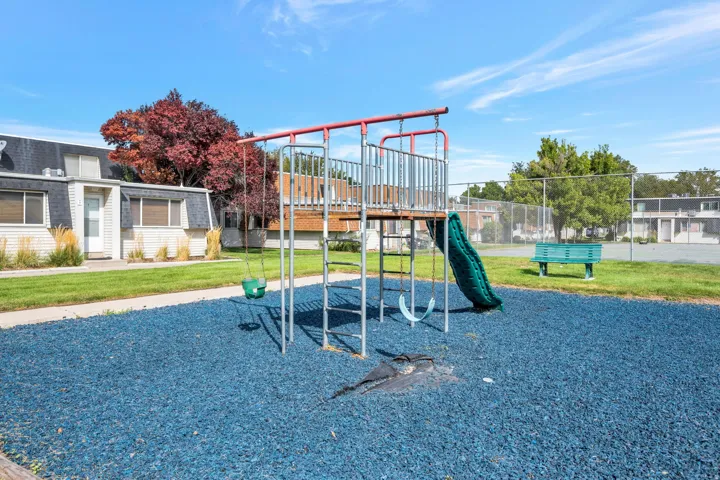 Playground area with a slide and swings, featuring a blue rubberized surface