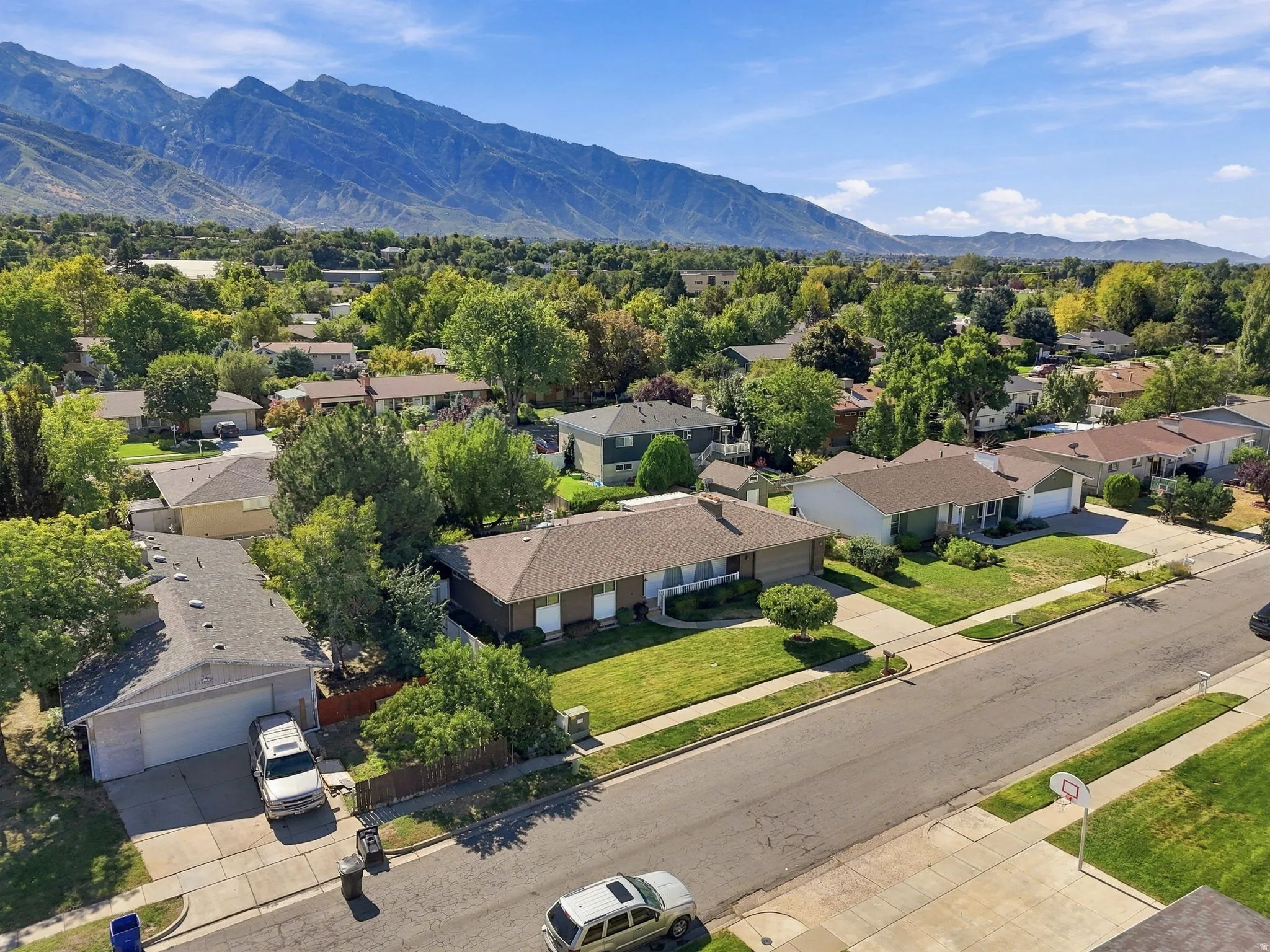 Mountain backdrop, suburban neighborhood, mature trees, residential street, detached garages
