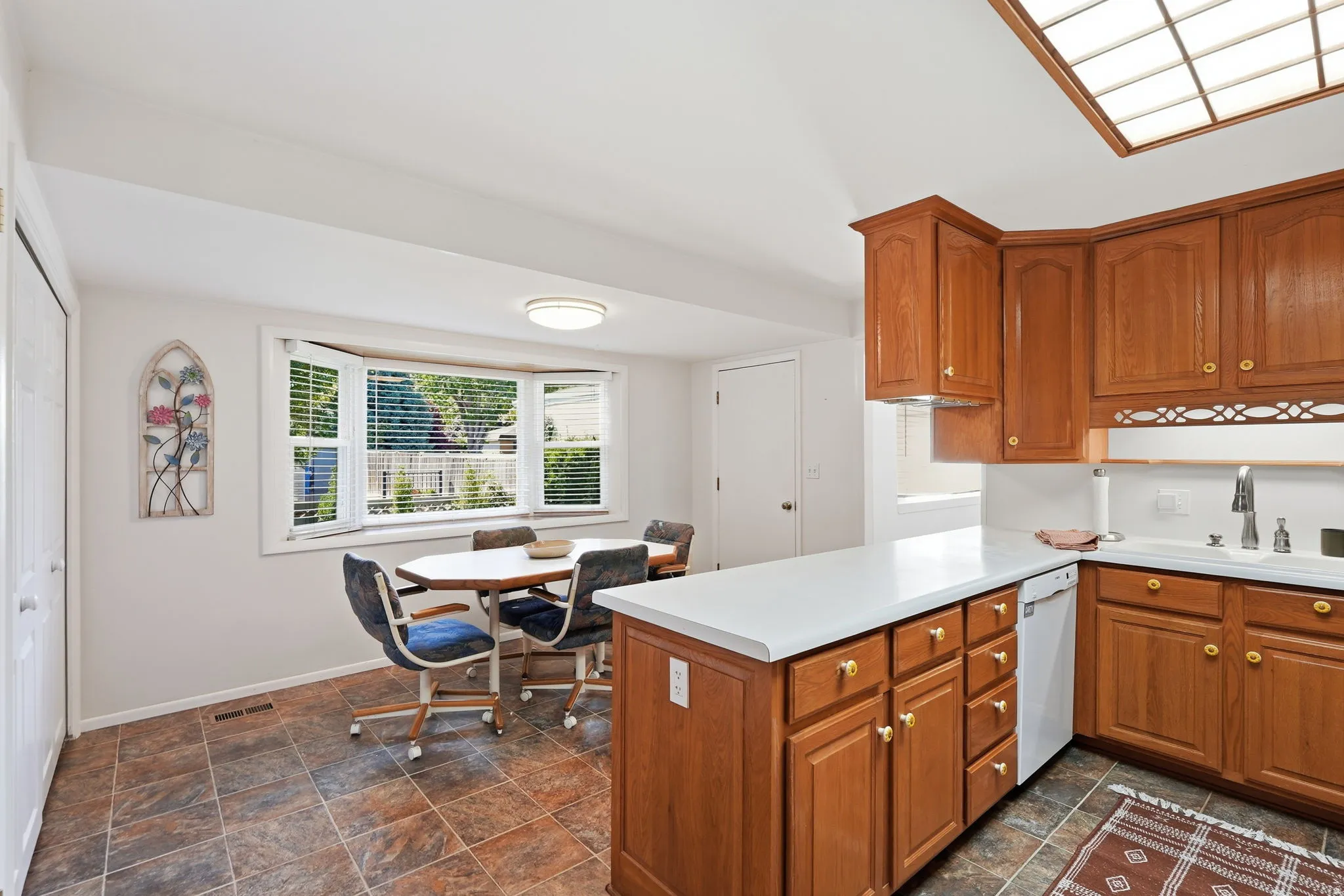 Kitchen featuring wood cabinetry, white countertops, tile flooring, and a bay window