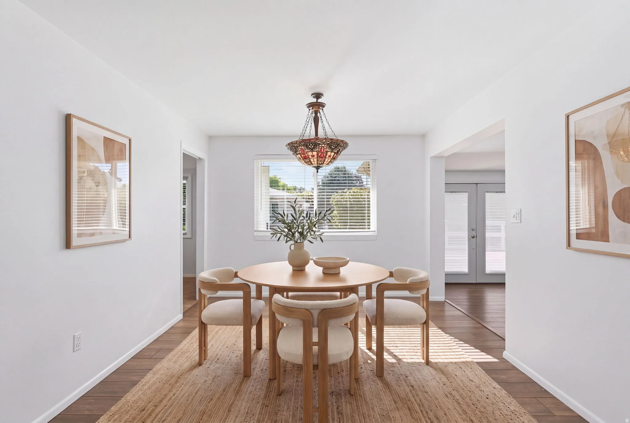 Wood-finish flooring with an area rug, white walls, and a decorative chandelier