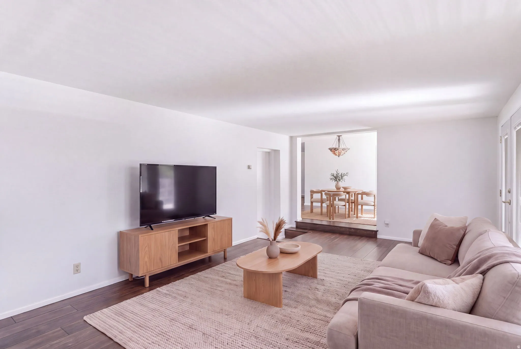 Hardwood-finish flooring, white walls, and a recessed dining area with a chandelier