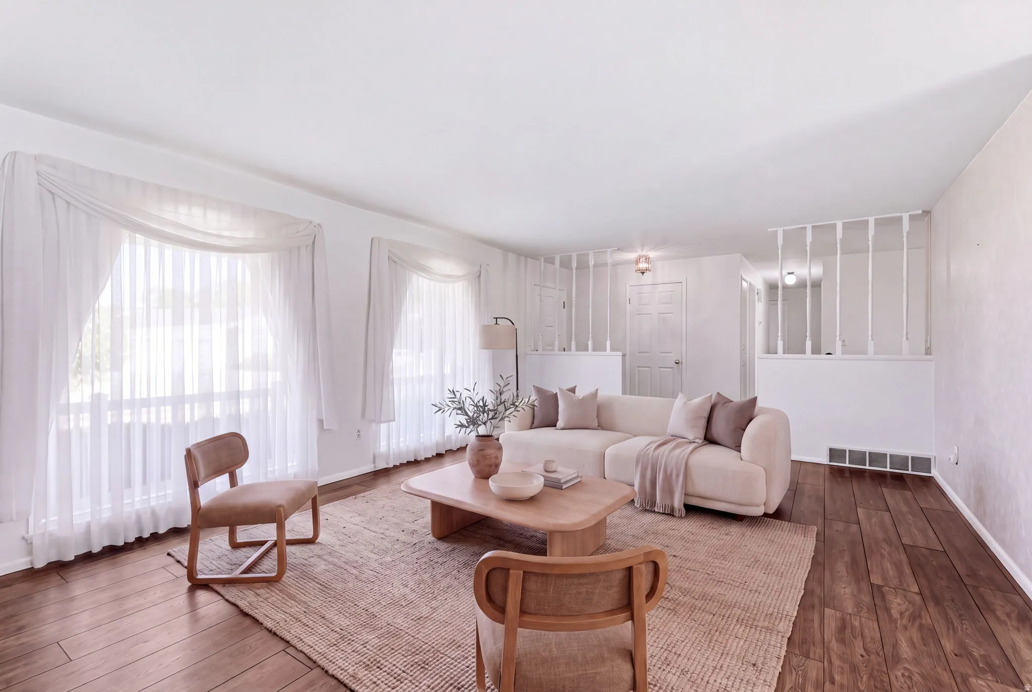Wood-finish flooring, white walls, two large windows, white ceiling, and a decorative interior half-wall