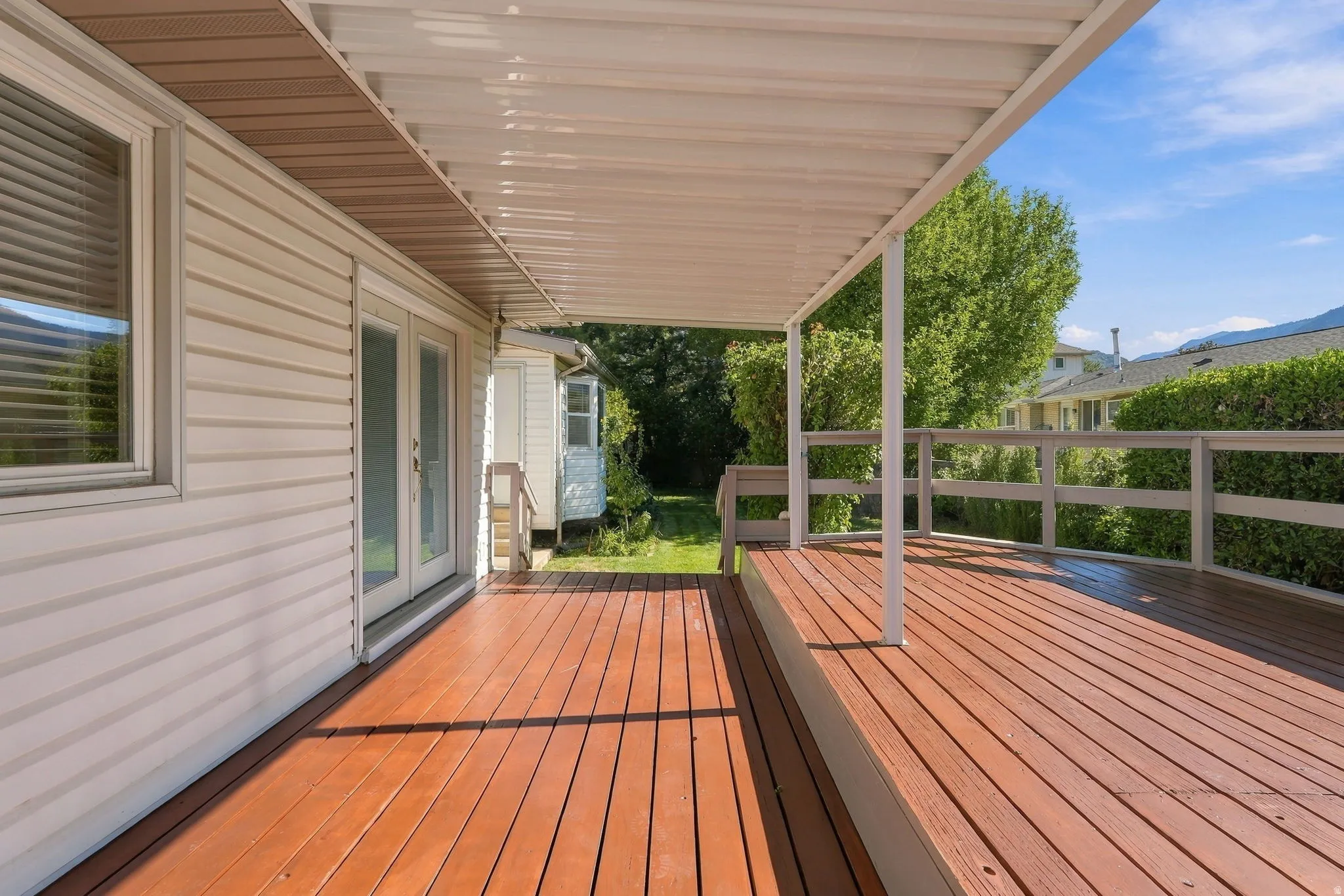 Expansive wood deck with a built-in bench, white railing, and a covered aluminum patio roof
