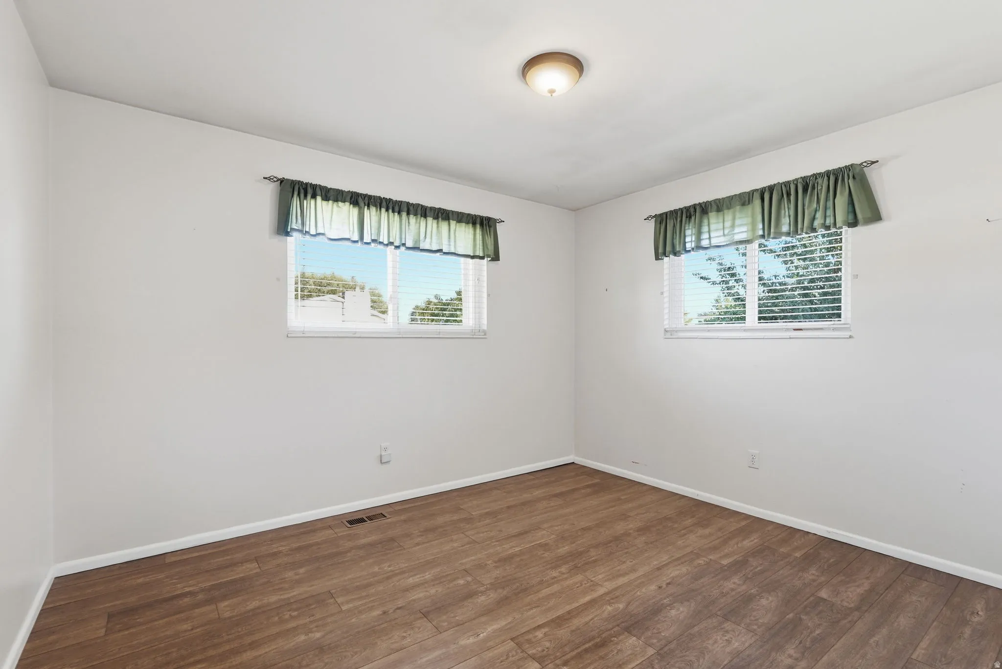 Wood-finish flooring, white walls, and a ceiling-mounted light fixture