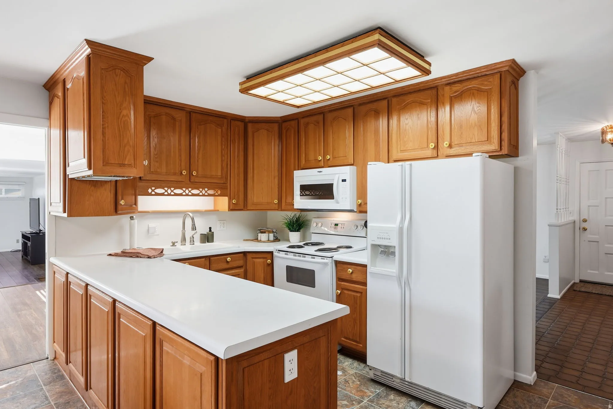 Kitchen featuring wood cabinetry, white countertops, a white refrigerator, and a built-in microwave
