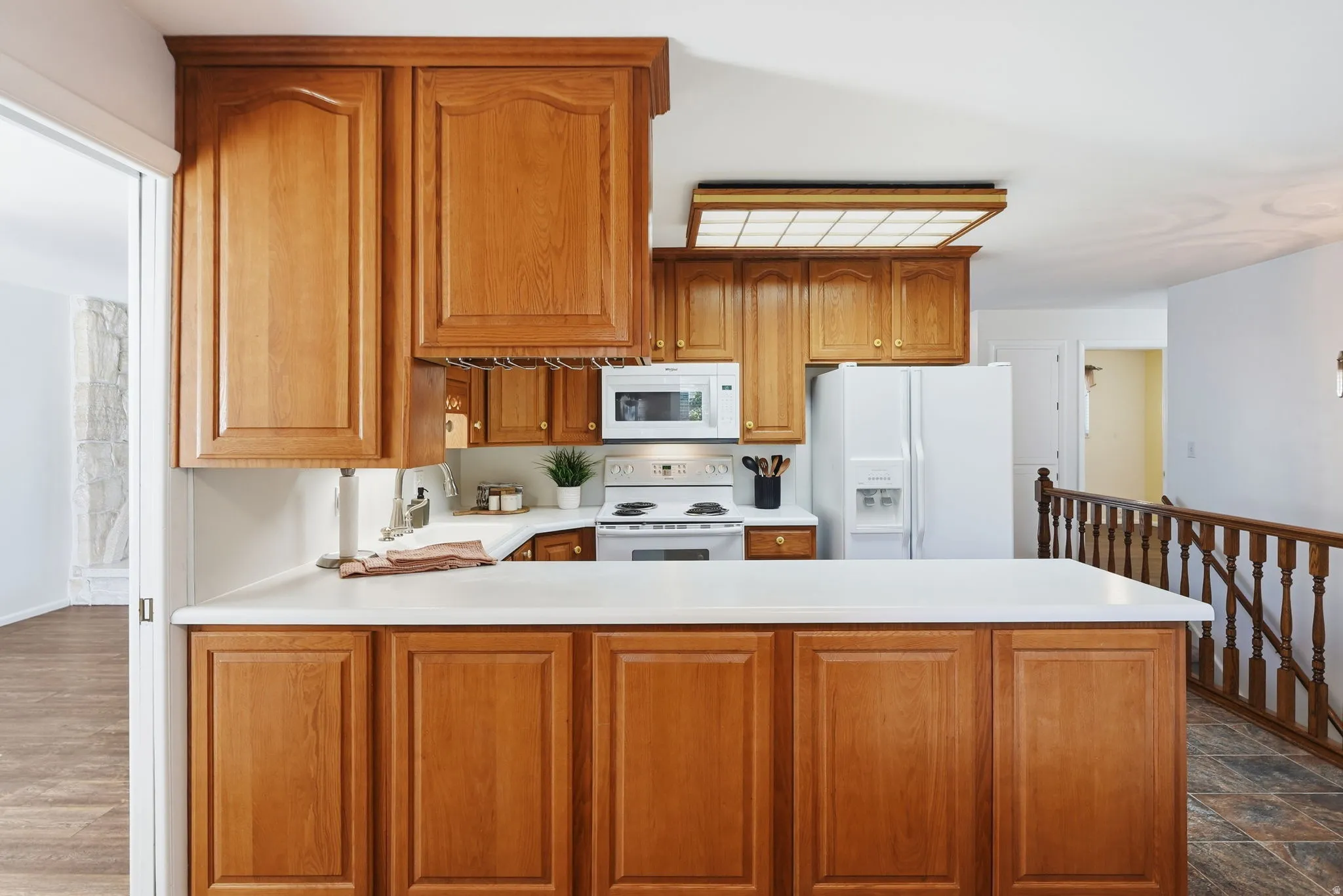 Kitchen featuring wood cabinetry, white countertops, a built-in microwave, white refrigerator, and a white range