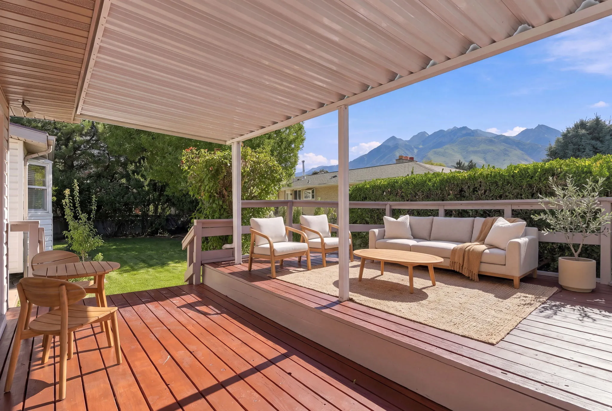 Covered multi-level deck with wood-finish flooring, white support columns, and garden access