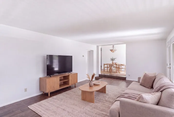 Hardwood-finish flooring, white walls, and a recessed dining area with a chandelier