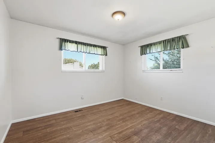 Wood-finish flooring, white walls, and a ceiling-mounted light fixture