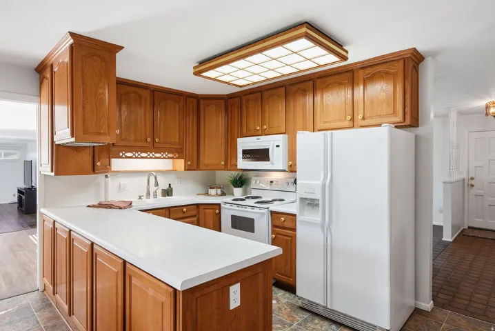 Kitchen featuring wood cabinetry, white countertops, a white refrigerator, and a built-in microwave