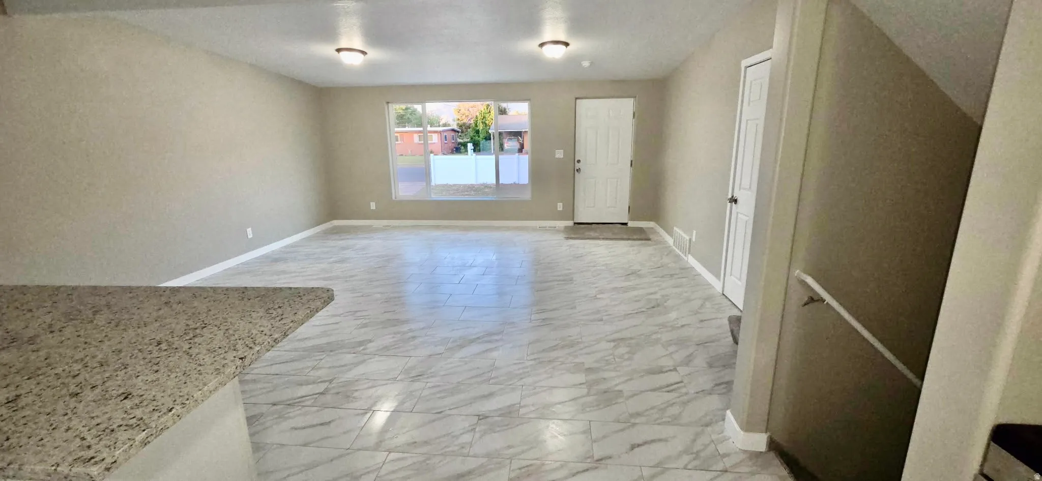 Spacious living area featuring large format tile flooring, neutral wall tones, and recessed lighting