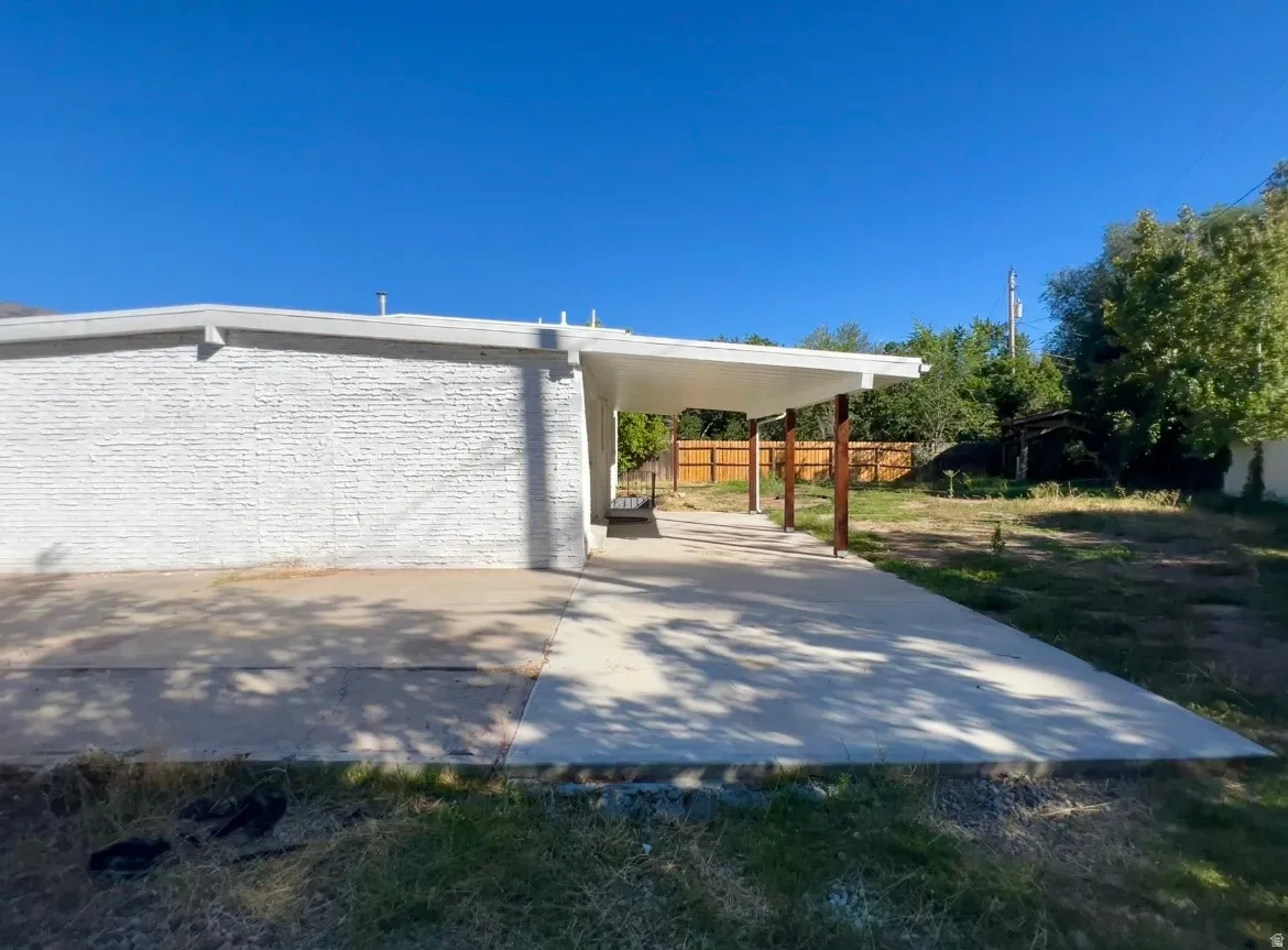 Expansive concrete patio with a covered outdoor area supported by wood columns