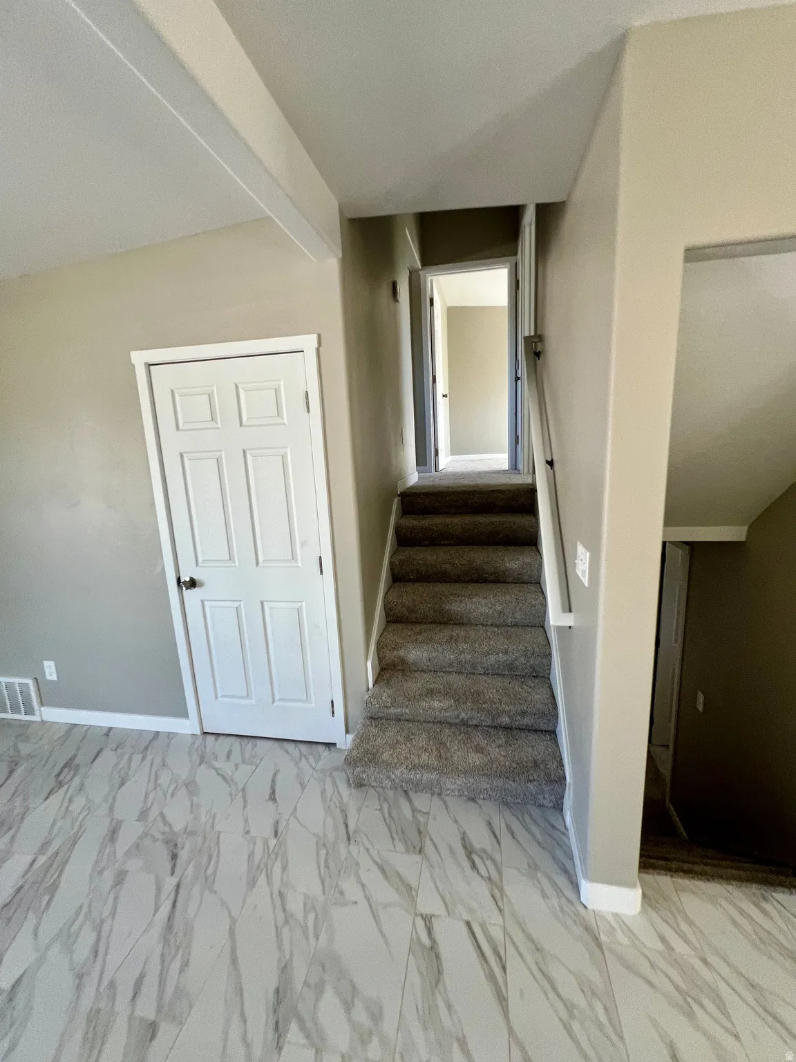 White paneled interior door, carpeted staircase, and tiled flooring