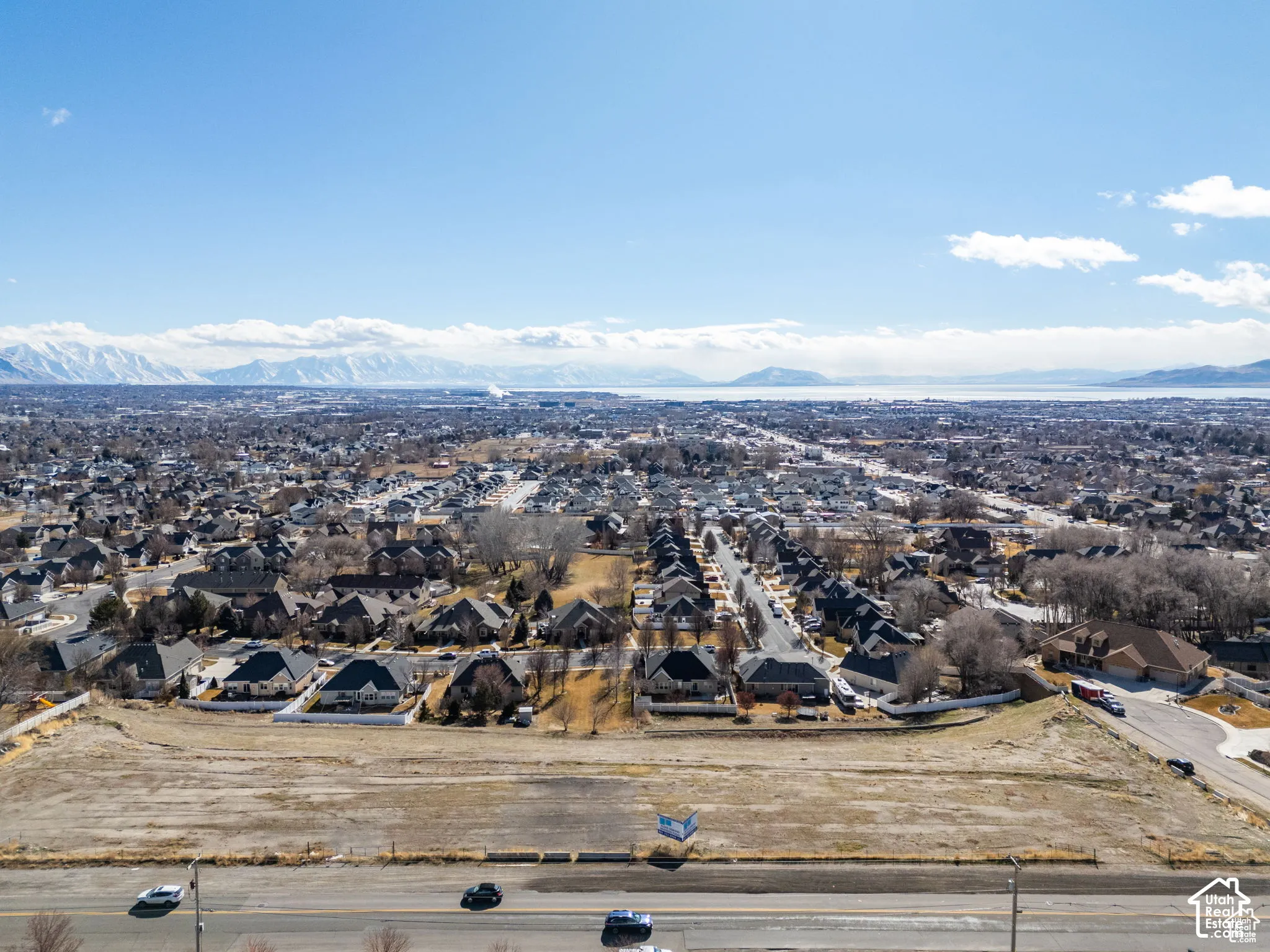 Expansive undeveloped land area with a surrounding residential community and distant mountain range backdrop