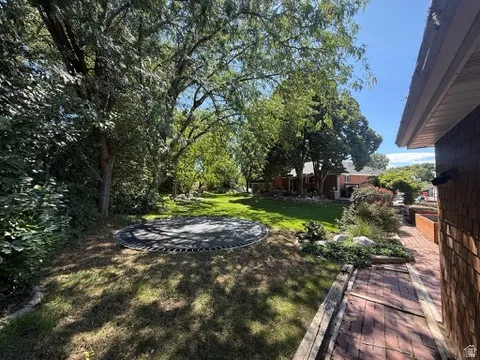 Expansive outdoor area featuring mature trees, a manicured lawn, and a brick pathway