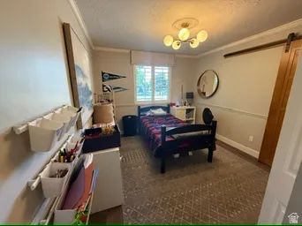 Wall-mounted storage system, window with white blinds, wood-finish flooring, crown molding, and a modern ceiling light fixture