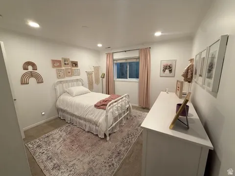 Recessed lighting illuminates the room, featuring a window with a roller shade, and a clean white dresser