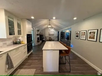 Kitchen featuring white shaker cabinetry, light-toned countertops, double wall ovens, and wood-finish flooring