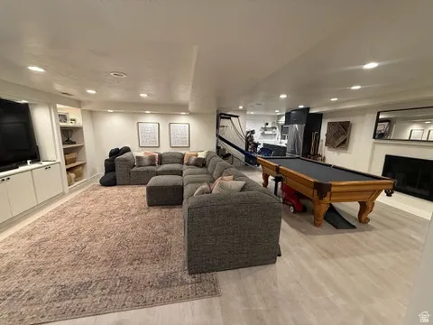Recessed lighting throughout, built-in shelving, fireplace with mantel, and wood-finish flooring