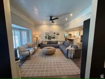 Recessed lighting, ceiling fan, bay window with plantation shutters, wood-finish flooring, and crown molding