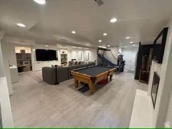 Recessed lighting, light wood-finish flooring, built-in media center, built-in shelving, and a white fireplace surround