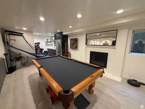 Recessed lighting throughout, wood-finish flooring, built-in fireplace, and a built-in wet bar with stainless steel appliances